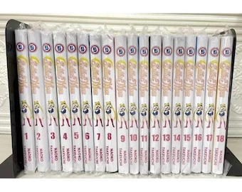 May include: A collection of eighteen Sailor Moon manga volumes. Each book features a white cover with the title, a character illustration, and volume number. The spines display the series title and author's name. The books are arranged in numerical order.