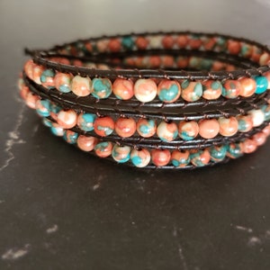 May include: A multi-strand leather wrap bracelet with orange, white, and turquoise beads.