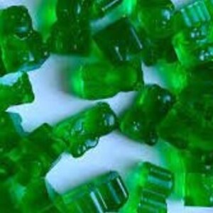 May include: Assortment of green gummy sweets in various shapes, including bears, cars, and rectangles.
