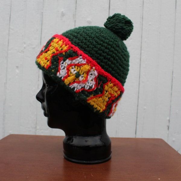 1970s handmade crocheted ski hat, cuffed beanie with pom-pom, dark green with yellow, white, and red on band, acrylic