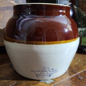 May include: A brown and white glazed stoneware crock with a blue crown and the number 2 on the bottom.