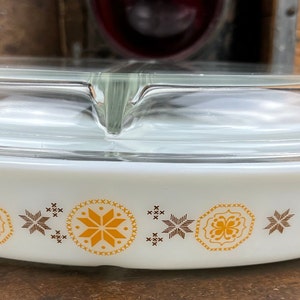 May include: White oval casserole dish with a clear glass lid. The dish has a brown and yellow geometric pattern around the edge.