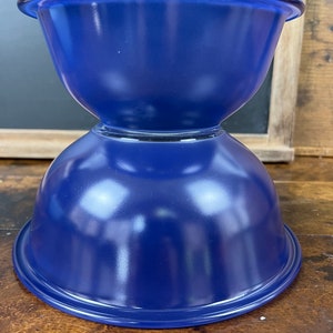May include: A set of two blue nesting bowls. The bowls are made of ceramic and have a glossy finish.