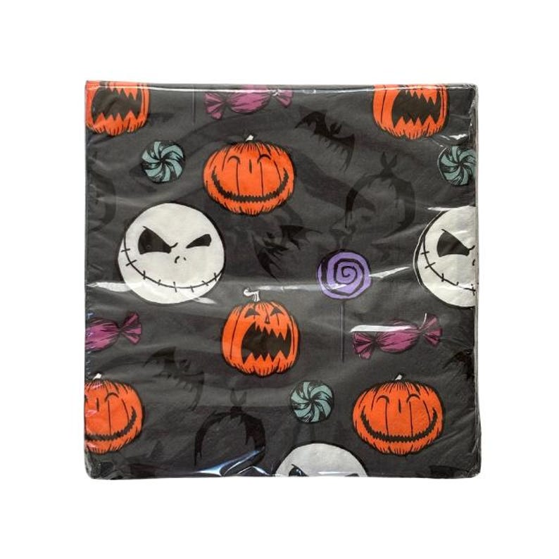 May include: A package of black Halloween-themed paper napkins. The napkins feature a repeating pattern of orange jack-o'-lanterns, Jack Skellington faces, bats, and candies in purple, teal, and pink. The napkins are wrapped in clear plastic.