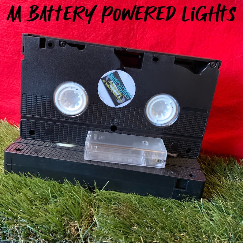 May include: A black VHS tape with a clear plastic case. The tape has a sticker on it that says "Wackystars" and "entertainment for all". The tape is sitting on top of a green grassy surface.
