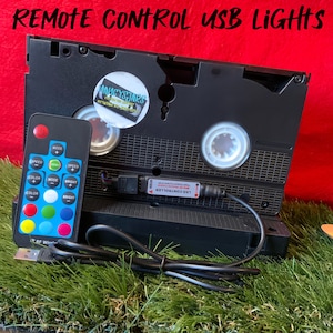 May include: A black VHS cassette tape with a USB cable and a remote control. The remote control has buttons for speed, mode, color, and brightness. The text "LED CONTROLLER" is printed on the USB cable.