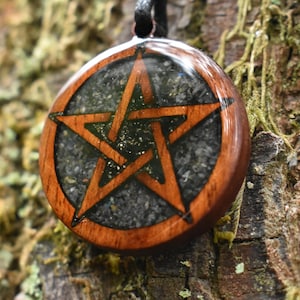 May include: A wooden pendant with a five-pointed star inside. The star is outlined in brown and the background is filled with black glitter.