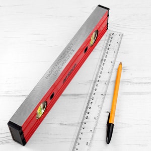 May include: A red and silver spirit level with a black handle. The level has a message engraved on it that reads "Happy Father's Day, Love Holly XX".