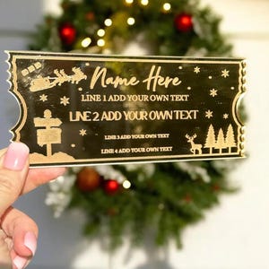 Pode incluir: Bilhete de Natal em acr&iacute;lico dourado com um design de rena e &aacute;rvores. O bilhete tem o texto "Name Here" e "LINE 1 ADD YOUR OWN TEXT" e "LINE 2 ADD YOUR OWN TEXT".