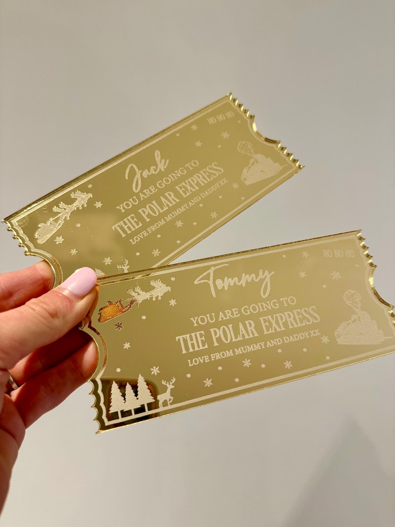 Pode incluir: Dois bilhetes dourados com um design de trem. Os bilhetes dizem "You are going to The Polar Express" e s&atilde;o personalizados com os nomes "Jack" e "Tommy".