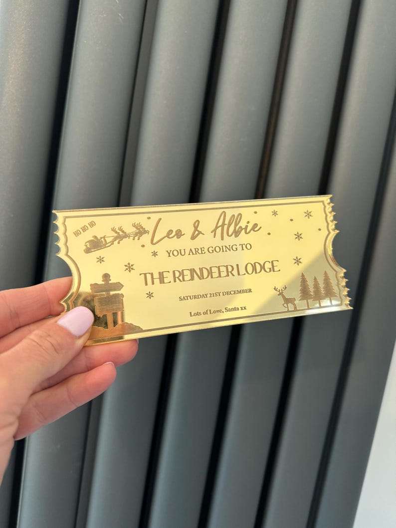 Pode incluir: Bilhete dourado com o texto "Leo & Albie * You are going to * The Reindeer Lodge * Saturday 21st December * Lots of Love, Santa xx" e uma ilustra&ccedil;&atilde;o de uma rena e pinheiros.