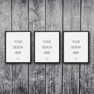 Peut inclure: Trois cadres photo noirs avec des passe-partout blancs accrochés à un mur en bois gris. Les cadres sont tous de la même taille et portent le texte "YOUR DESIGN HERE" au centre.