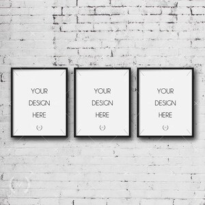 Peut inclure: Trois cadres photo noirs avec des passe-partout blancs accrochés à un mur en briques blanches. Les cadres sont vides et portent le texte "YOUR DESIGN HERE" imprimé en noir à l'intérieur de chaque cadre.