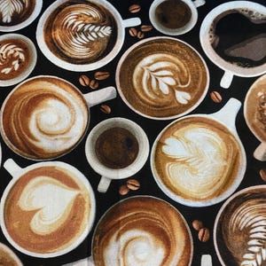 Könnte beinhalten: Stoffmuster mit verschiedenen Kaffeetassen mit Latte-Art-Designs in Braun- und Cremetönen auf schwarzem Hintergrund. Kaffeebohnen sind um die Tassen verstreut und erzeugen ein Café-Thema.