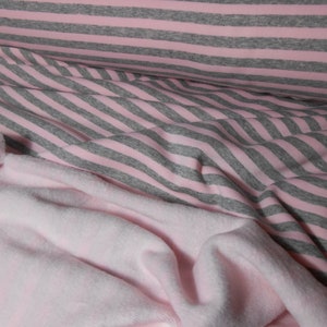 Könnte beinhalten: Rosa-grauer gestreifter Stoff mit einem weichen rosa Fleece-Stoff darunter.