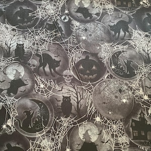 Op de afbeelding: Zwart-witte Halloween-stof met een herhalend patroon van manen, vleermuizen, spinnen, uilen, pompoenen, heksen en huizen. De stof is bedekt met een spinnenwebontwerp.