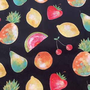 Op de afbeelding: Een zwarte stof met een herhalend patroon van verschillende soorten fruit en groenten. Het patroon omvat citroenen, sinaasappels, peren, ananas, aardbeien, watermeloenen en kersen.