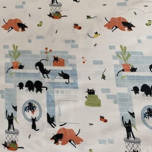 Può includere: Tessuto bianco con un motivo ripetuto di gatti neri, topi, calzini e piante. I gatti sono in varie pose, alcuni nascosti sotto coperte arancioni, altri sopra i bidoni della spazzatura o le lavatrici.