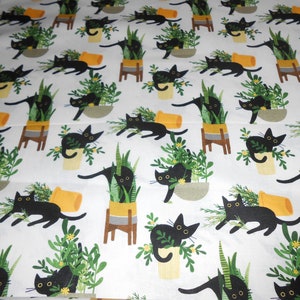 Könnte beinhalten: Weißer Stoff mit einem sich wiederholenden Muster aus schwarzen Katzen, Topfpflanzen und gelben Blumenakzenten. Die Katzen sind in verschiedenen Posen, einige interagieren mit den Pflanzen. Die Töpfe sind in Gelb-, Braun- und Grautönen gehalten.