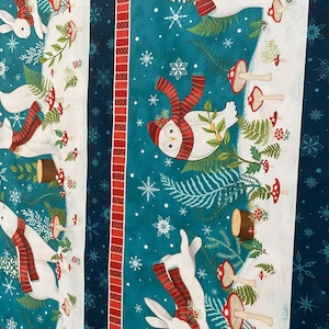 Puede incluir: Tela con una escena de bosque invernal. Conejos, zorros y un búho blancos llevan bufandas rojas. El diseño incluye setas, copos de nieve y helechos sobre un fondo a rayas turquesa, blanco y rojo.