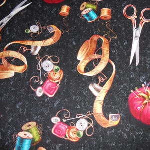 Könnte beinhalten: Ein schwarzer Stoff mit einem sich wiederholenden Muster aus Nähzubehör. Das Muster enthält Garnrollen, Maßband, Nähnadeln, Knöpfe und eine Schere.