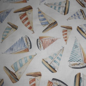 Op de afbeelding: Witte stof met een herhalend patroon van blauwe en rode zeilboten. De zeilboten hebben witte strepen en zijn geplaatst tegen een witte achtergrond.