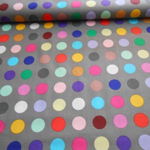 Könnte beinhalten: Grauer Stoff mit einem sich wiederholenden Muster aus bunten Punkten. Die Punkte sind in verschiedenen Schattierungen von Rot, Blau, Grün, Gelb, Rosa und Lila.