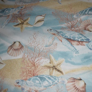 Puede incluir: Una tela azul y blanca con un patrón repetido de tortugas marinas, estrellas de mar, conchas marinas y corales. La tela tiene un aspecto de acuarela.