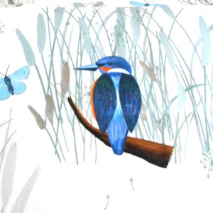Op de afbeelding: Waterverfillustratie van een blauw-oranje ijsvogel op een bruine tak. De afbeelding toont riet, hoog gras en een blauwe vlinder tegen een witte achtergrond. Het kunstwerk heeft een natuurthema.