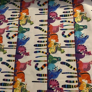 Puede incluir: Tela blanca con un patrón repetido de animales de dibujos animados coloridos. Los animales, en varios colores como naranja, rosa, verde y azul, tienen colas a rayas. La tela presenta rayas verticales y líneas horizontales.