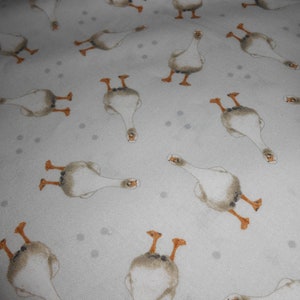 Könnte beinhalten: Ein weißer Stoff mit einem sich wiederholenden Muster aus braunen Gänsen. Die Gänse sind in verschiedene Richtungen ausgerichtet und haben ein einfaches Design.