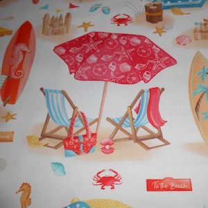Op de afbeelding: Een strandthema stof met een rood-wit gestreepte strandparasol, twee strandstoelen, een surfboard, een zandkasteel en de tekst "To The Beach".