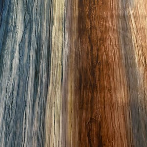 Può includere: Opera d'arte astratta con striature verticali di colore. Il lato sinistro presenta tonalità blu e grigie, che sfumano verso il beige e il marrone a destra. La trama ricorda le venature del legno o l'acqua che scorre, creando un effetto visivo dinamico.