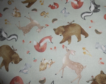 May include: A light green fabric with a repeating pattern of woodland animals, including deer, foxes, bears, and skunks. The animals are illustrated in a whimsical style with brown, orange, and black accents.