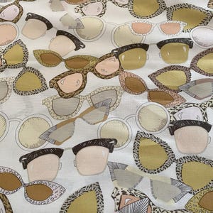 Könnte beinhalten: Ein weißer Stoff mit einem sich wiederholenden Muster aus verschiedenen Sonnenbrillen-Stilen in Braun, Schwarz und Beige.