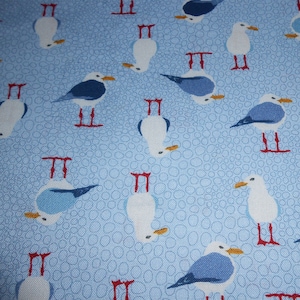 Può includere: Un tessuto blu con un motivo ripetitivo di gabbiani bianchi con zampe rosse. I gabbiani sono rivolti in direzioni diverse e si trovano in varie posizioni.