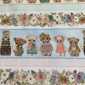 Op de afbeelding: Een witte stof met een herhalend patroon van bruine teddyberen die verschillende outfits en bloemranden dragen. De beren dragen hoeden, jurken en overalls. De bloemen zijn in tinten roze, paars en blauw.