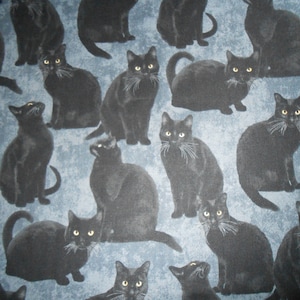 Può includere: Un tessuto blu con un motivo ripetitivo di gatti neri. I gatti sono in varie pose, alcuni seduti, alcuni in piedi e alcuni guardano verso l'alto.
