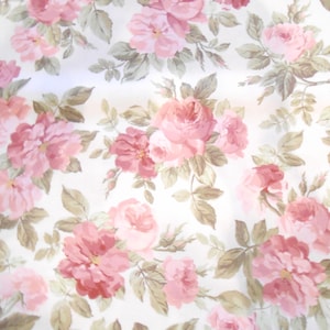 Könnte beinhalten: Ein weißer Stoff mit einem rosafarbenen Blumenmuster. Der Stoff ist mit rosafarbenen Rosen mit grünen Blättern bedeckt.