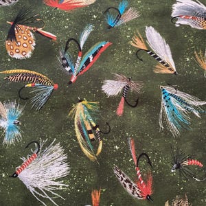 May include: A green fabric with a repeating pattern of colourful fishing flies. The flies are made of feathers and have hooks.