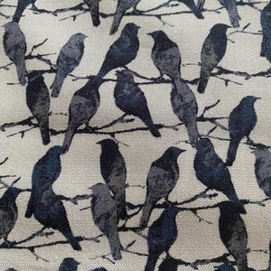 Puede incluir: Una tela con un patrón repetido de pájaros azul oscuro y gris posados ​​en ramas finas y oscuras. Los pájaros están en varias poses y el fondo es de color beige claro. El diseño general tiene un aspecto natural y ligeramente rústico.