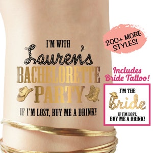 May include: Gold temporary tattoo with the text "I'm with Lauren's Bachelorette Party. If I'm lost, buy me a drink!" and a cowboy hat and boots graphic. A separate gold temporary tattoo with the text "I'm the Bride. If I'm lost, buy me a drink!" and a cowboy hat graphic.