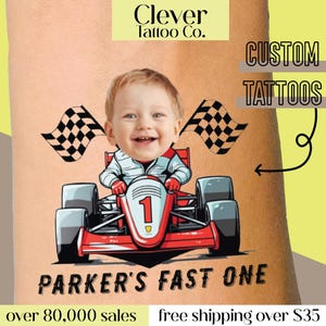 Op de afbeelding: Een aangepaste tijdelijke tatoeage van een kind dat een rode raceauto bestuurt met zwart-wit geblokte vlaggen. De tekst "PARKER'S FAST ONE" staat onder de auto. De tekst "Clever Tattoo Co." en "CUSTOM TATTOOS" staat bovenaan de afbeelding.