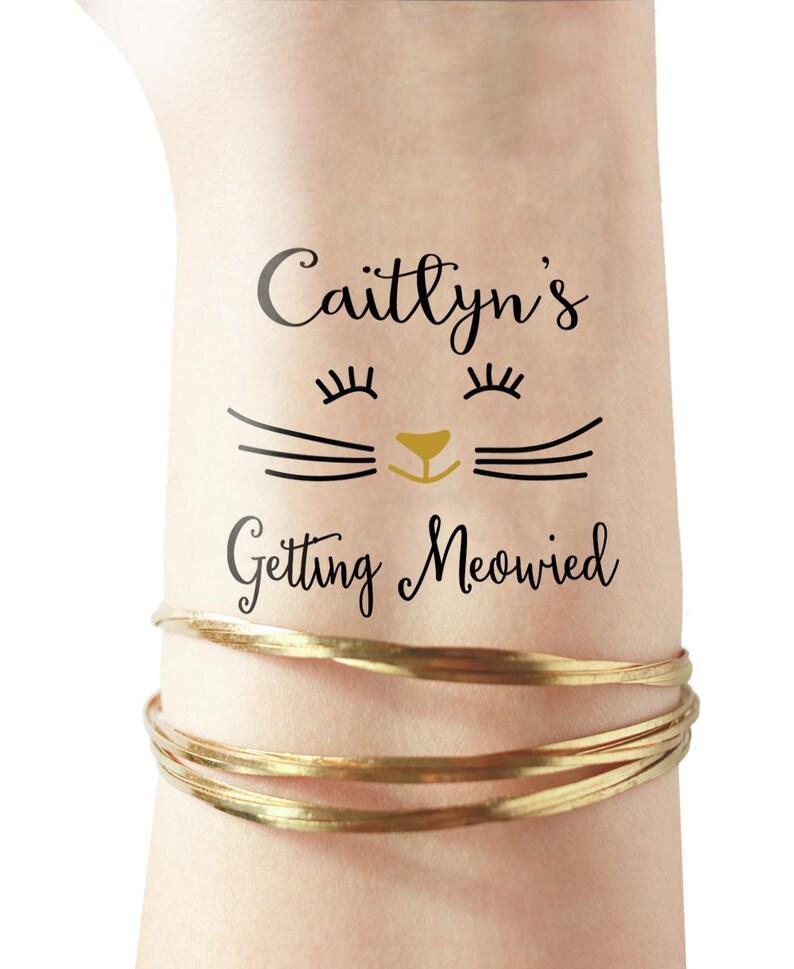 Puede incluir: Un tatuaje temporal con una cara de gato negro y el texto "Caitlynn's Getting Meowed" en letra negra.