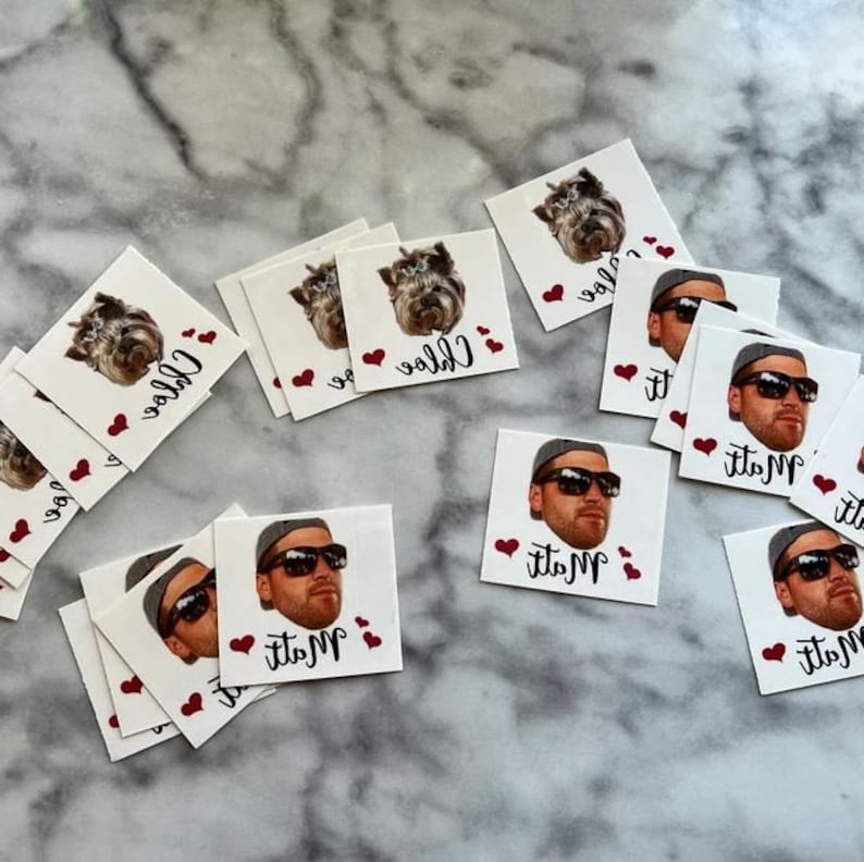 May include: A set of 10 personalized temporary tattoos with red hearts and names. The tattoos feature a dog and a man's face.