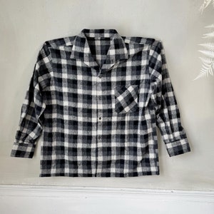 May include: A black and white plaid flannel shirt with long sleeves and a button-up front.