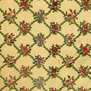 May include: A yellow fabric with a repeating pattern of green vines and colorful flowers. The flowers are in shades of red, pink, purple, and blue.