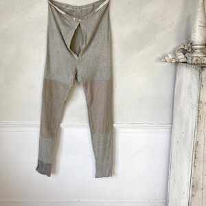 May include: A pair of gray long underwear with a button fly and brown striped accents on the legs.