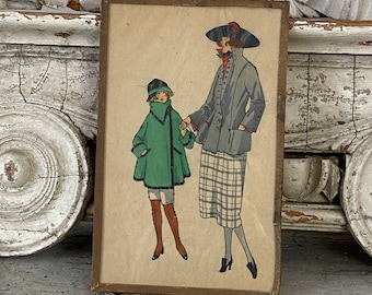 May include: A framed vintage illustration of two women wearing hats and coats. The woman on the left is wearing a green coat and a black hat. The woman on the right is wearing a gray coat and a black and red hat. The illustration is on a beige background.