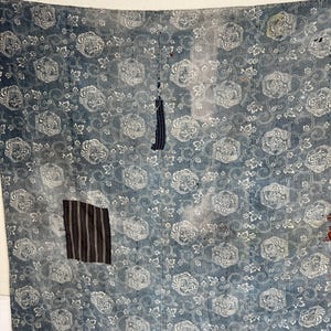 May include: A blue fabric with a white floral pattern. The fabric has been patched with different fabrics in a few places.